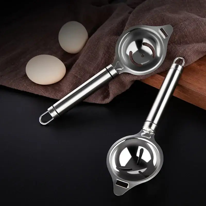 Two polished stainless steel egg white separators with smiley face circular bowls and sleek handles for yolk filtering