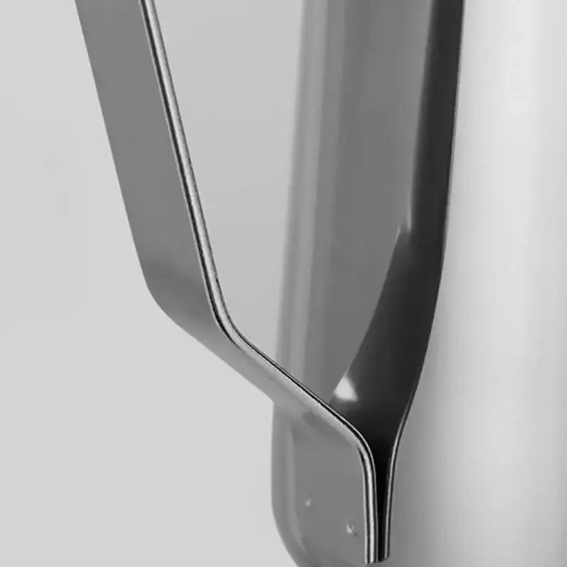 The sleek handle of a polished stainless steel frothing cup for kitchen latte art by decorbites frothing cup