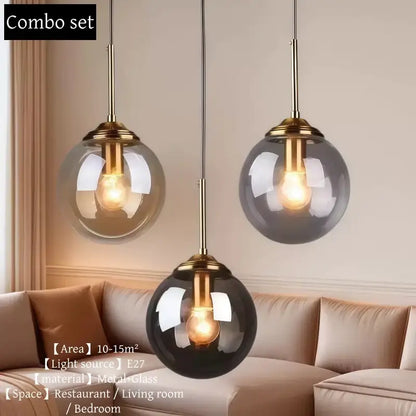 Set of three glass pendant lights with polished steel brass fixtures in clear smoky gray and black for dining room