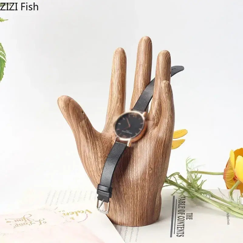 Polished wood grain hand palm sculpture holding a rose gold watch with black dial on rustic wooden palm sculpture