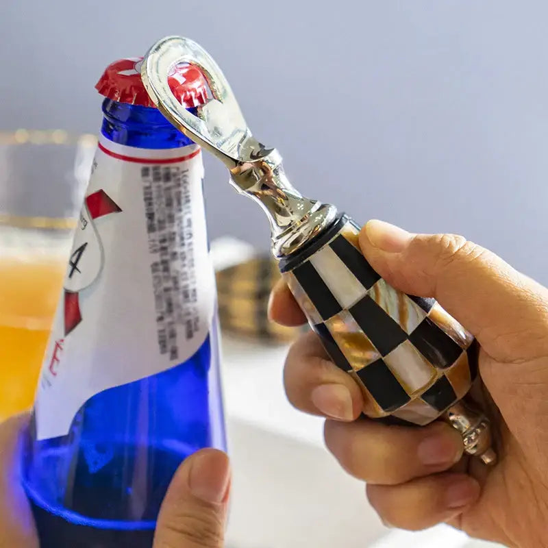 A sleek silver beer bottle opener with a black and white mother-of-pearl handle enhances the drinking experience