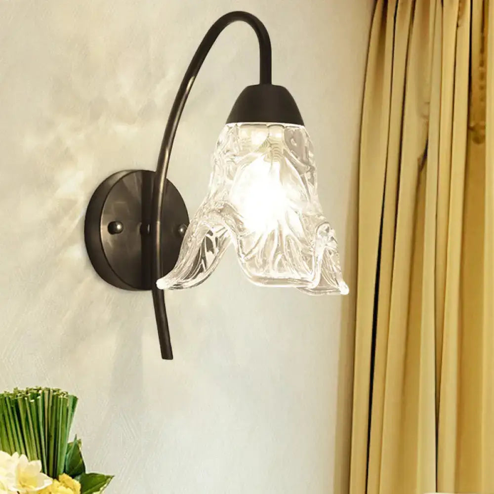 Post-modern black metal wall sconce with a clear crystal shade and intricate textured glass for bedroom use