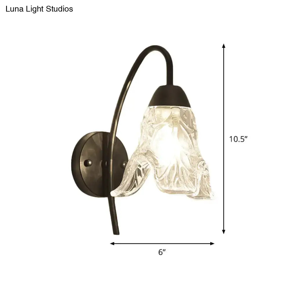 Post-modern black metal wall sconce with a clear crystal shade and textured glass for bedroom lighting