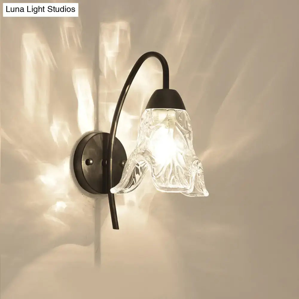 Post-modern black metal wall sconce featuring a clear crystal shade with intricate glass texture for bedroom use