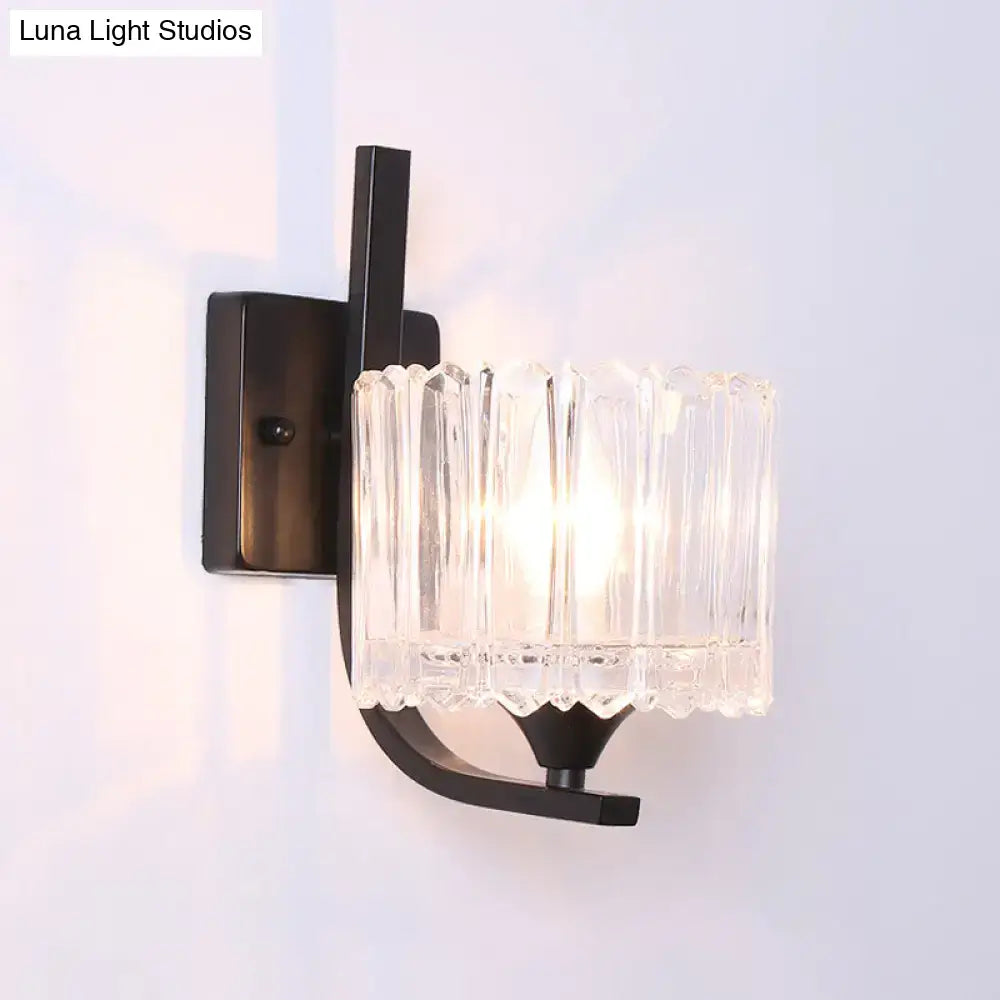 Post-modern black metal wall sconce with a clear crystal shade featuring a faceted glass design for bedroom use