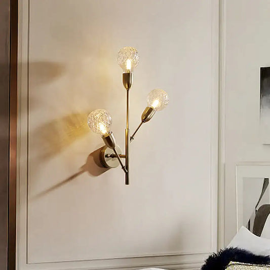 Post-modern brass wall light fixture with three illuminated clear lattice glass bulbs for bedroom use