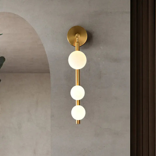 Post modern gold finish wall lamp with three frosted glass spheres aligned vertically for living room lighting