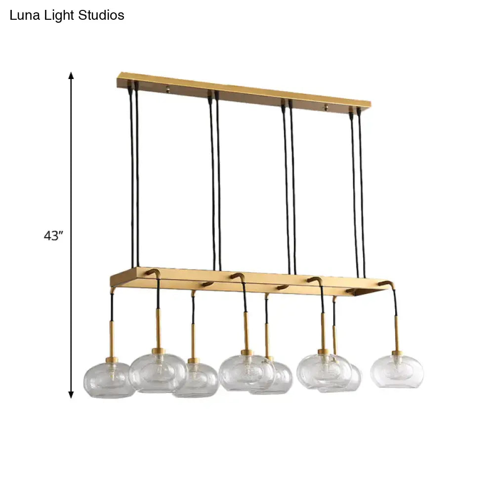 Gold-toned post-modern island chandelier with six clear glass globe shades suspended by black cords by DecorBites