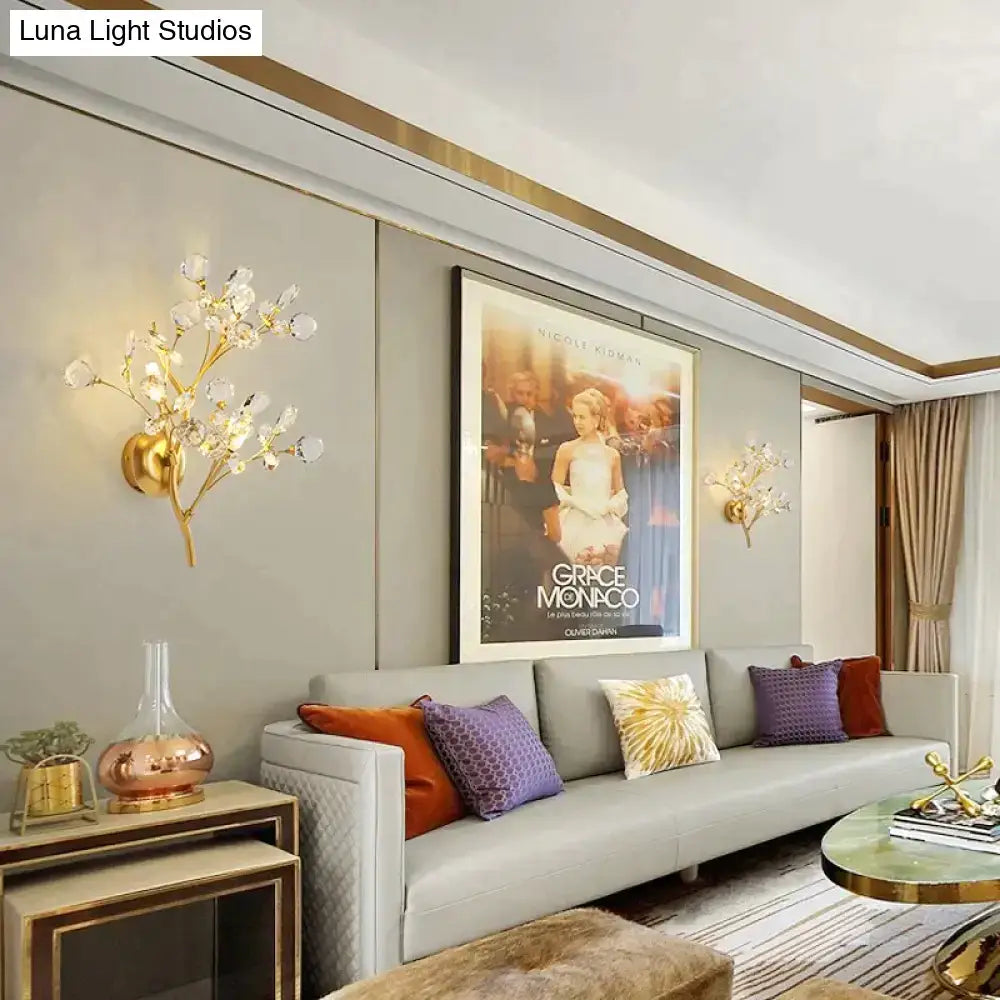 Post modern luxury gold-toned wall sconce with crystal-like blossoms in a modern luxury branch style for bedroom lighting