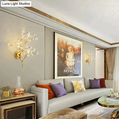 Post modern luxury gold-toned wall sconce with crystal-like blossoms in a modern luxury branch style for bedroom lighting