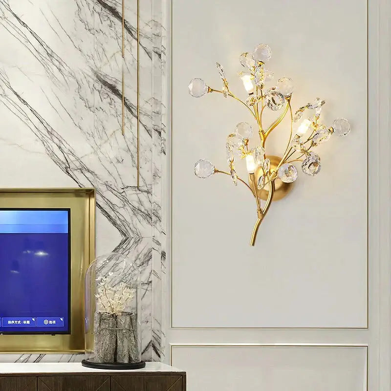 Post modern luxury gold-toned wall sconce with crystal accents in a modern luxury branch style for bedroom lighting