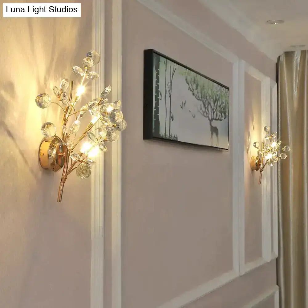 Post modern luxury gold-toned wall sconce with crystal branches and spherical accents for bedroom lighting