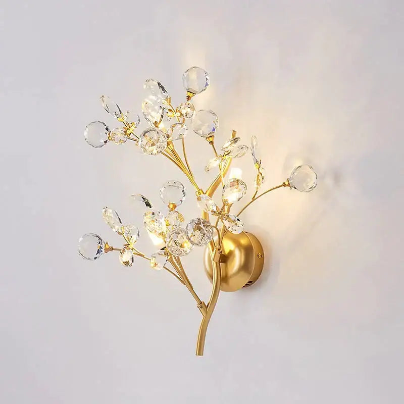 Post modern luxury gold-toned wall sconce with crystal branch and spherical accents for bedroom lighting