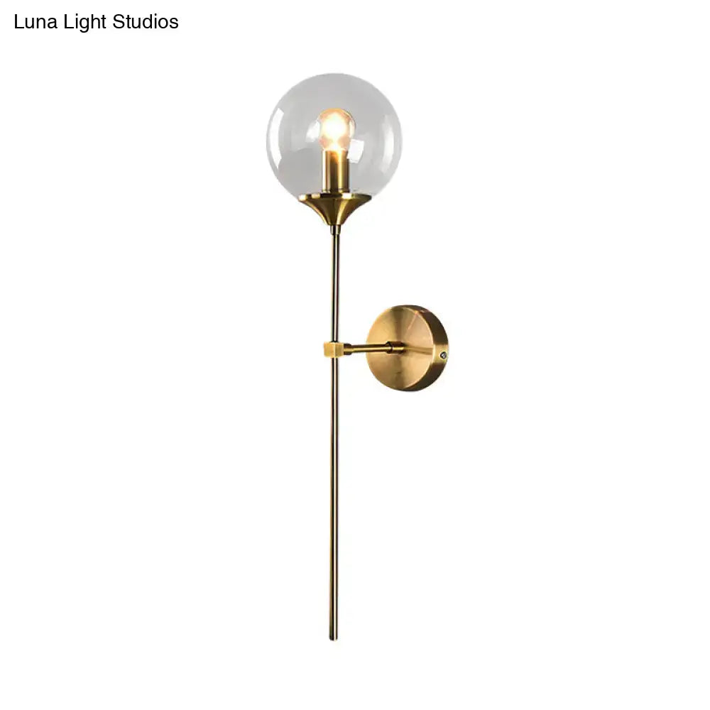 A sleek brass wall sconce with smoke grey and amber glass housing an exposed e27 bulb for bedroom use