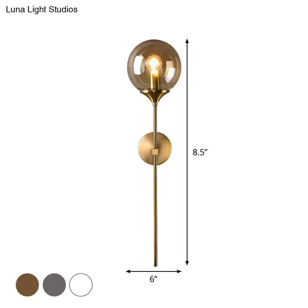 A sleek postmodern brass wall sconce with smoke grey glass and an e27 bulb for bedroom lighting