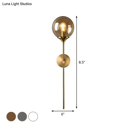 A sleek postmodern brass wall sconce with smoke grey glass and an e27 bulb for bedroom lighting