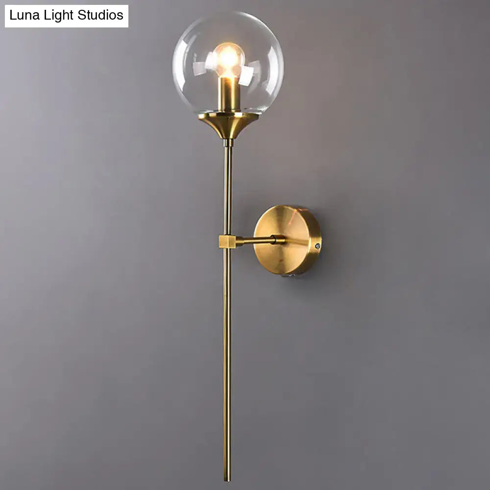 Brass-finished wall sconce with a clear glass globe housing an exposed e27 bulb in smoke grey for bedroom use