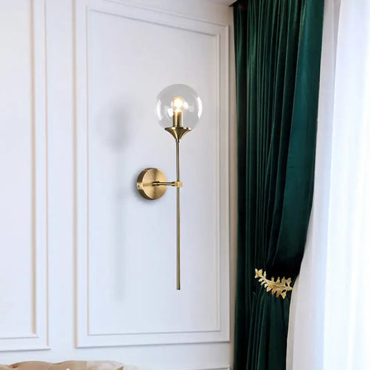 Gold-toned postmodern wall sconce with smoke grey glass globe and slender stem for e26 e27 bulb use in bedroom