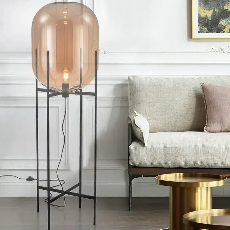Postmodern floor lamp with amber glass ball and slender black metal legs suitable for living room decorbites glass ball