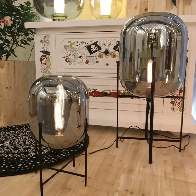 Shiny chrome-finished spherical floor lamp with black metal stand and amber glass ball for elegant living room decorbites glass ball