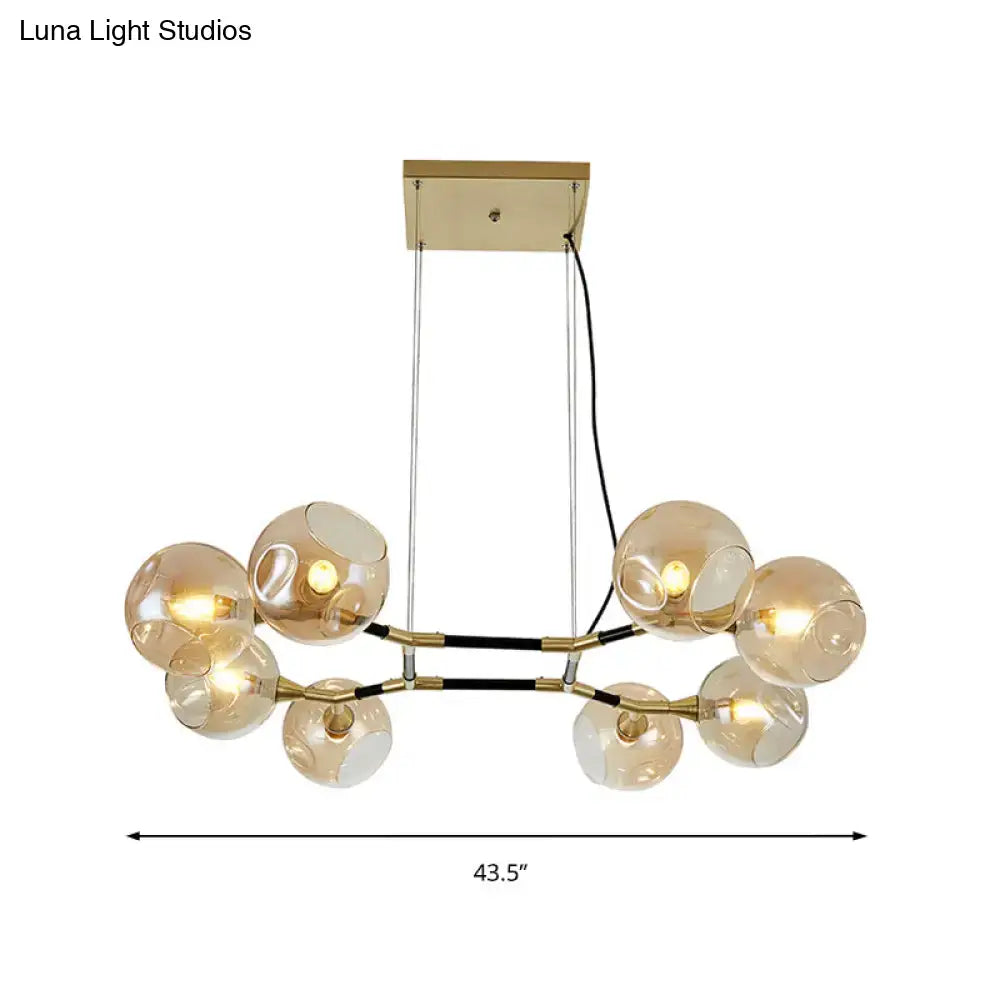Gold-toned modern chandelier with amber ball glass globe shades and adjustable cords for island lighting