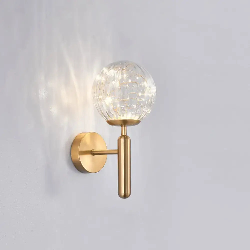 Gold-toned postmodern wall sconce with textured clear prismatic glass shade for modern style bedroom lighting