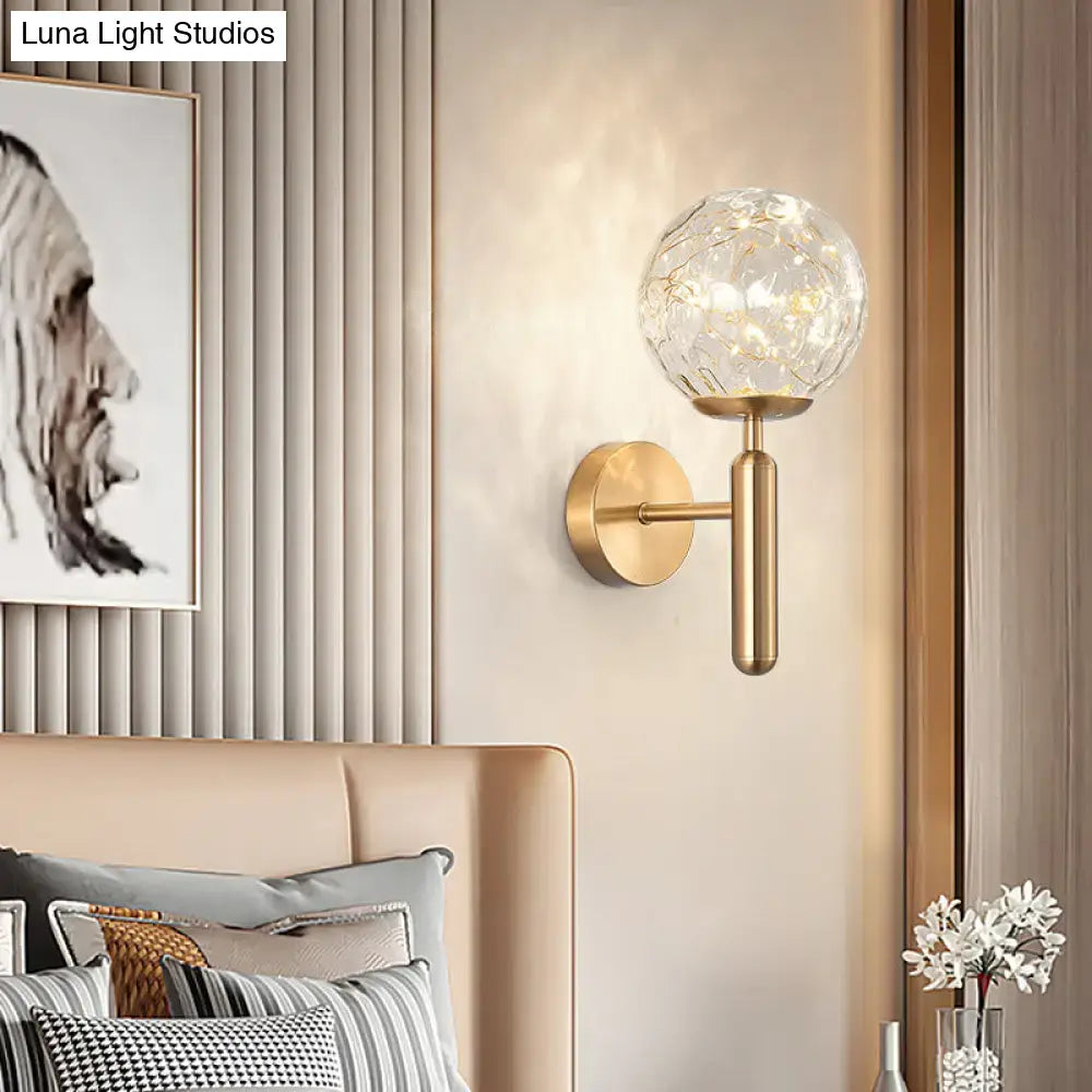 Gold-toned postmodern wall sconce with textured glass shade and golden leaf patterns for modern style bedroom lighting