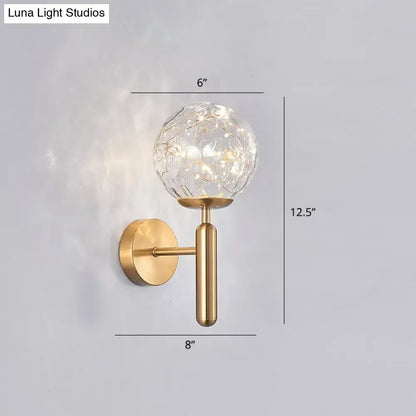Gold-toned postmodern wall sconce with crackled prismatic glass shade and warm led lights for modern style bedroom lighting
