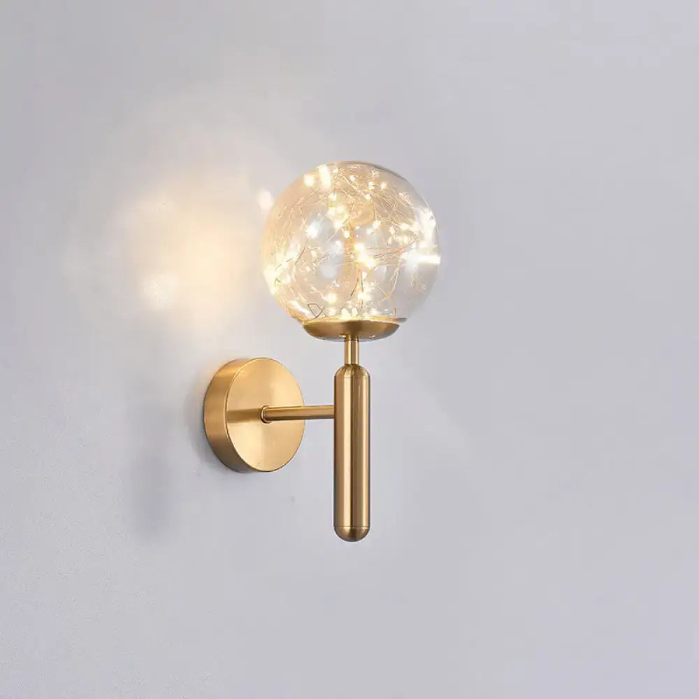 Postmodern gold-toned wall sconce with a spherical prismatic glass shade and delicate string lights in modern style