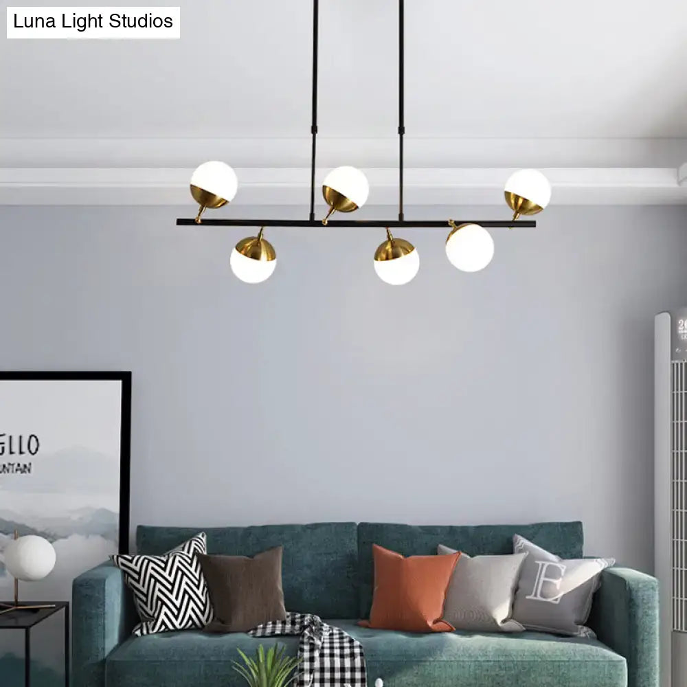 Modern black metal island ceiling light with five white glass globes and gold-toned fixtures for kitchen pendant lighting