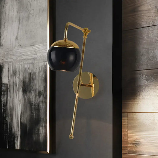 Postmodern black and gold swing arm wall sconce with clear spherical glass shade and adjustable arm for bedroom lighting