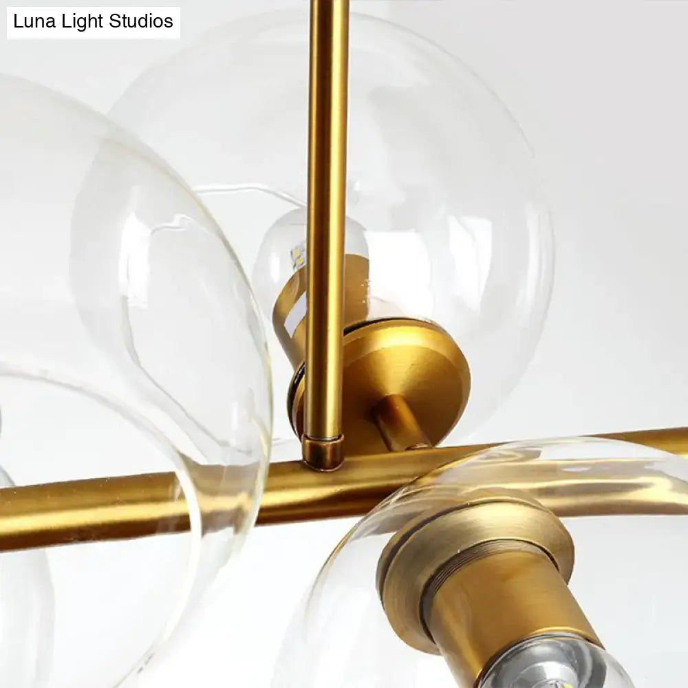 Gold-toned metal chandelier with clear glass globe shades featuring clear smoke grey light type for dining room use