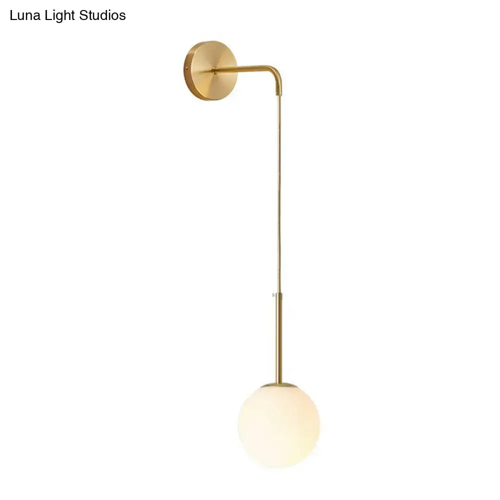Gold-toned minimalist wall lamp with sleek curved arm and frosted glass globe shade for bedroom lighting