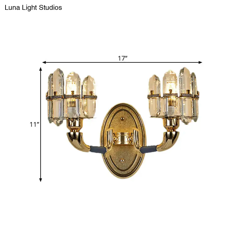 Gold finished wall mount lamp with two arms each holding three clear crystal shades for bedroom use
