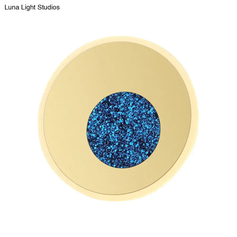 Postmodern blue round sconce light fixture with a circular gold-toned frame and vibrant blue glittery center for bedroom use