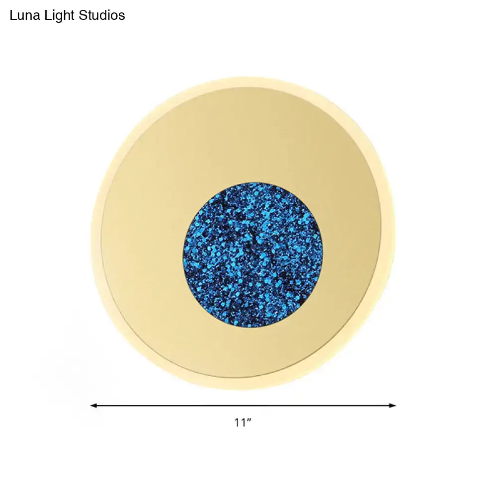 Postmodern blue round sconce light fixture with gold-toned ring and vibrant blue glittery center for bedroom use