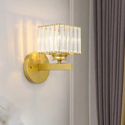 Gold-finished brass black wall sconce with rectangular crystal block shade featuring vertical glass rods for bedroom use