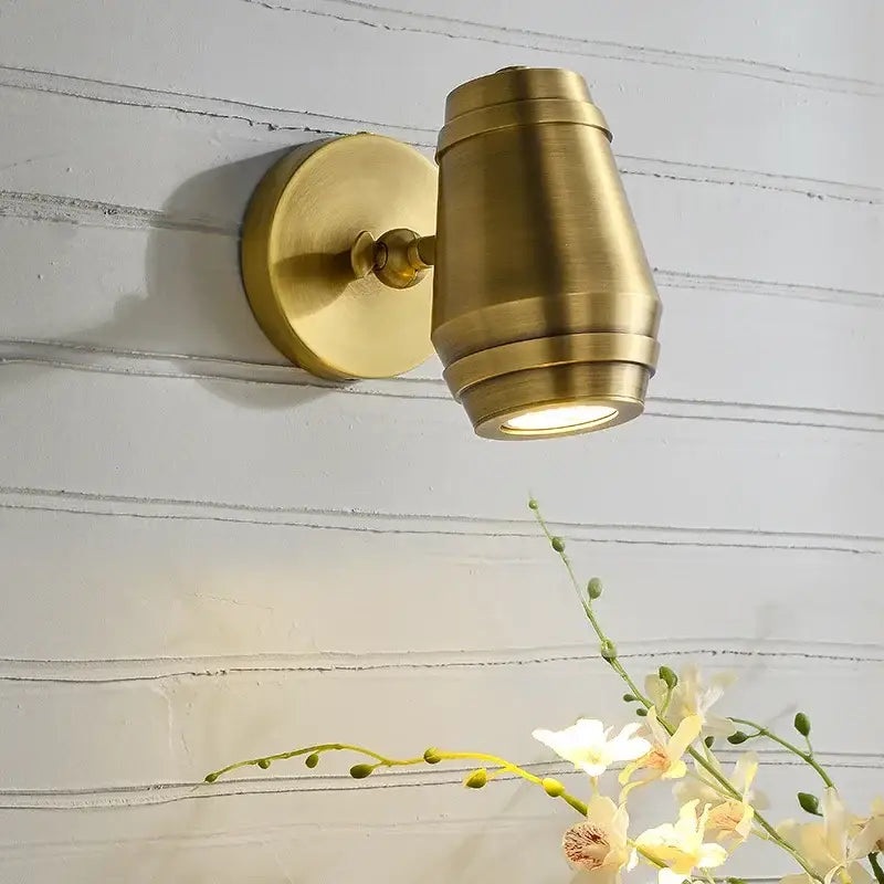 Postmodern brass wall lamp with cylindrical adjustable spotlight and circular base ideal for bedroom decorbites brass wall lamp