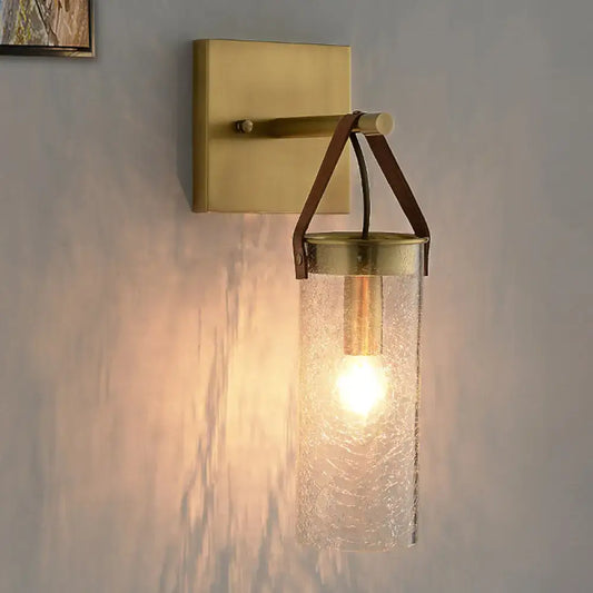Postmodern brass wall sconce with clear crack glass cylinder and leather strap accents for dining room lighting