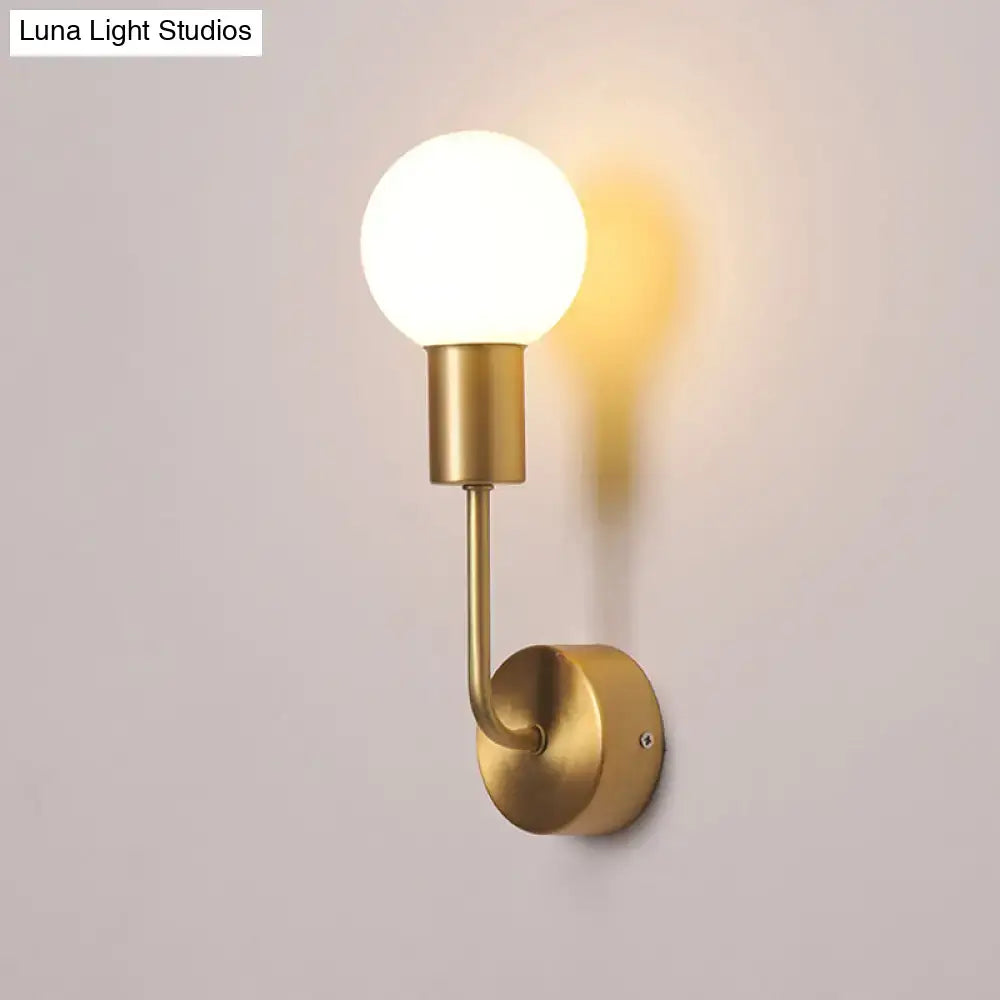 Postmodern brass wall sconce with white glass geometric frosted bulb and minimalist curved metal arm for living room