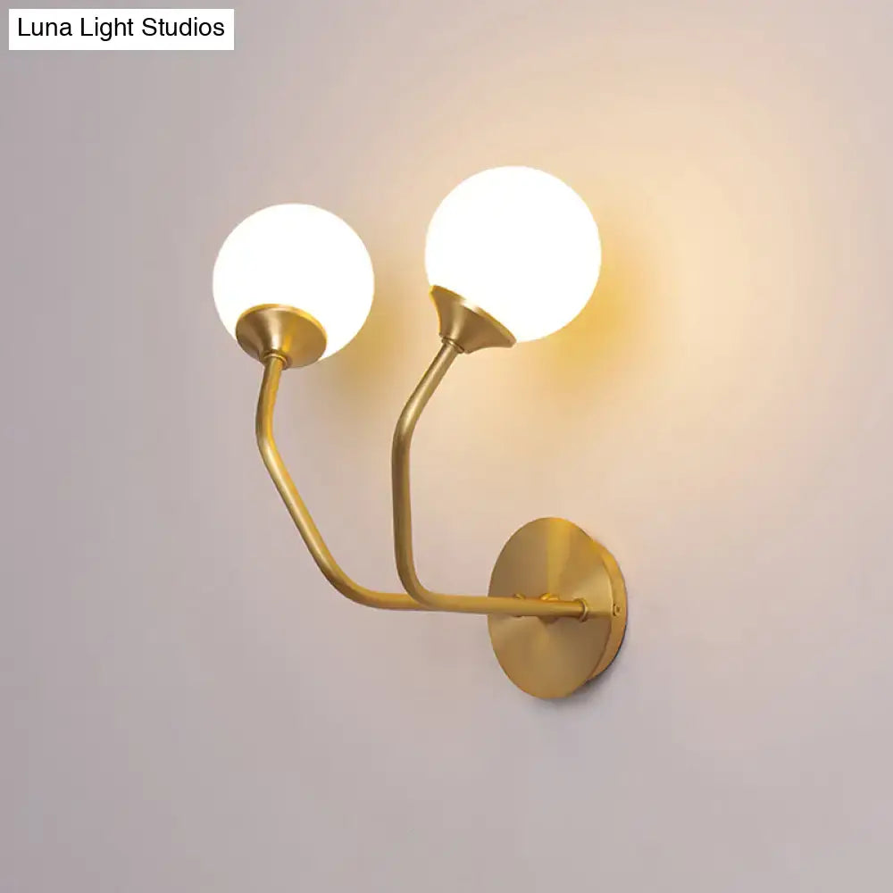 Postmodern brass wall sconce with gold-toned curved arms and white glass geometric frosted globes for living room
