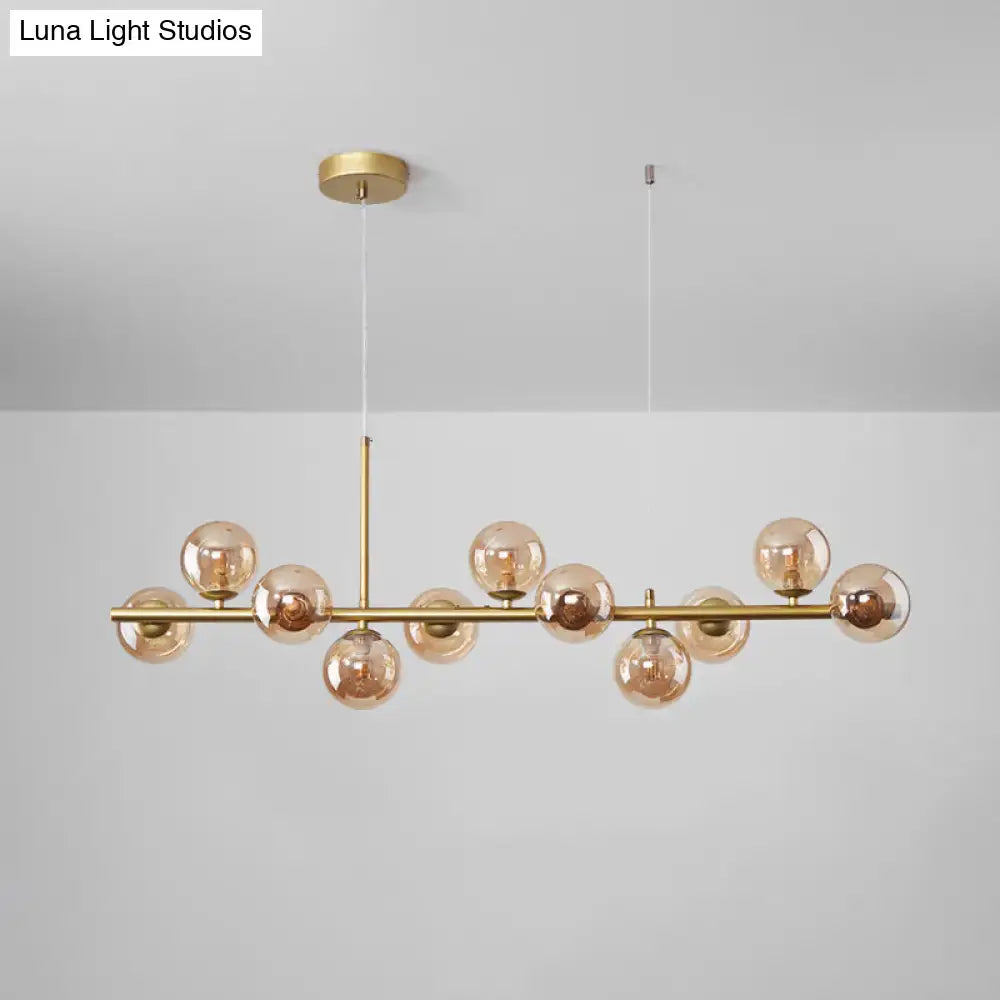 Gold-toned DecorBites™ postmodern pendant light with amber glass globe bulbs on metallic bar for kitchen lighting