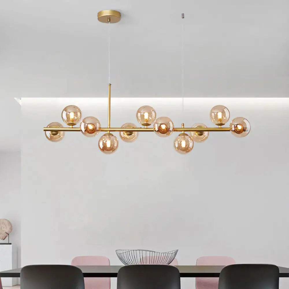 Gold-toned modern pendant light with amber glass globes on a sleek horizontal bar from DecorBites™ for kitchen use