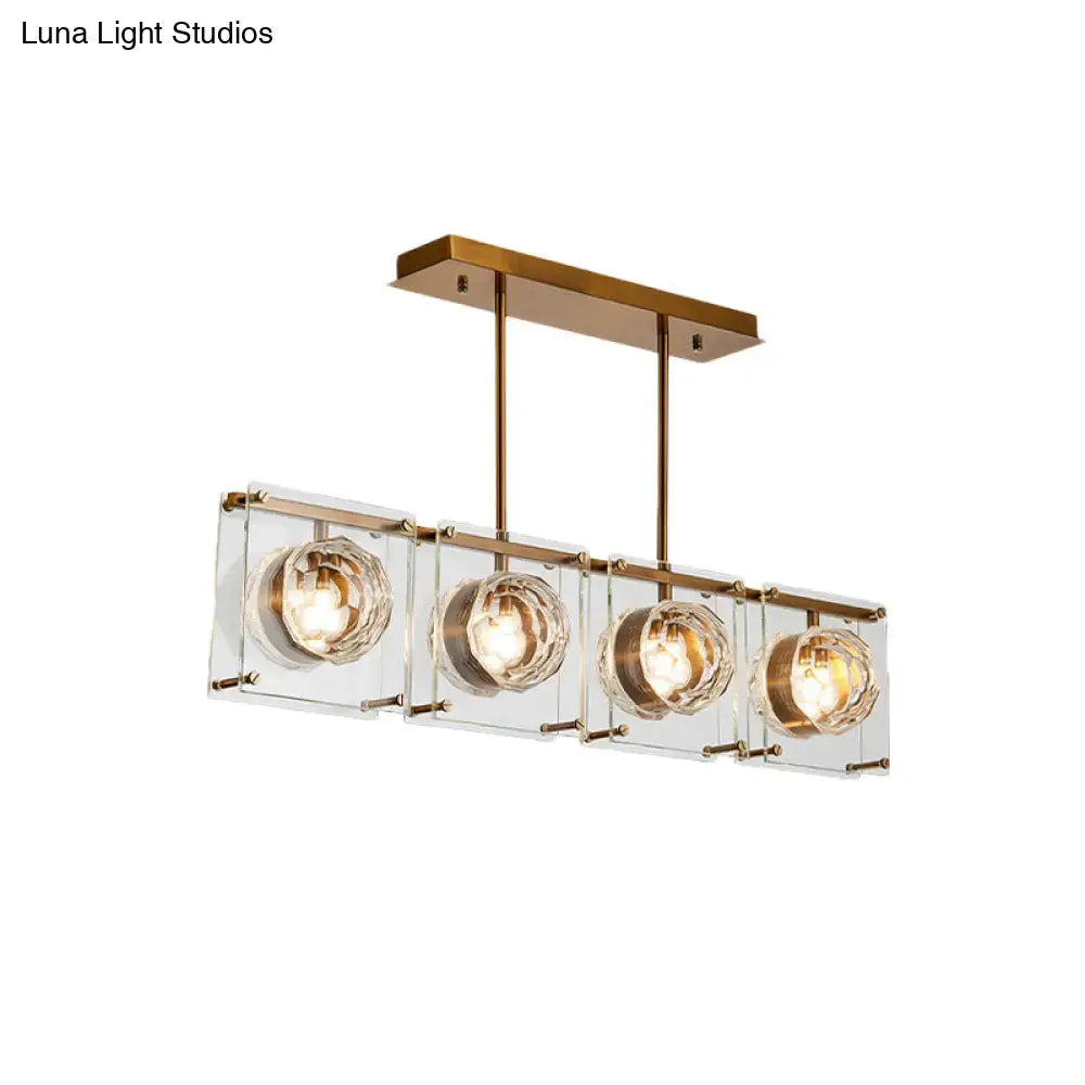 Postmodern gold and clear glass kitchen island light with four brass-finished pendant cube shades and warm bulbs