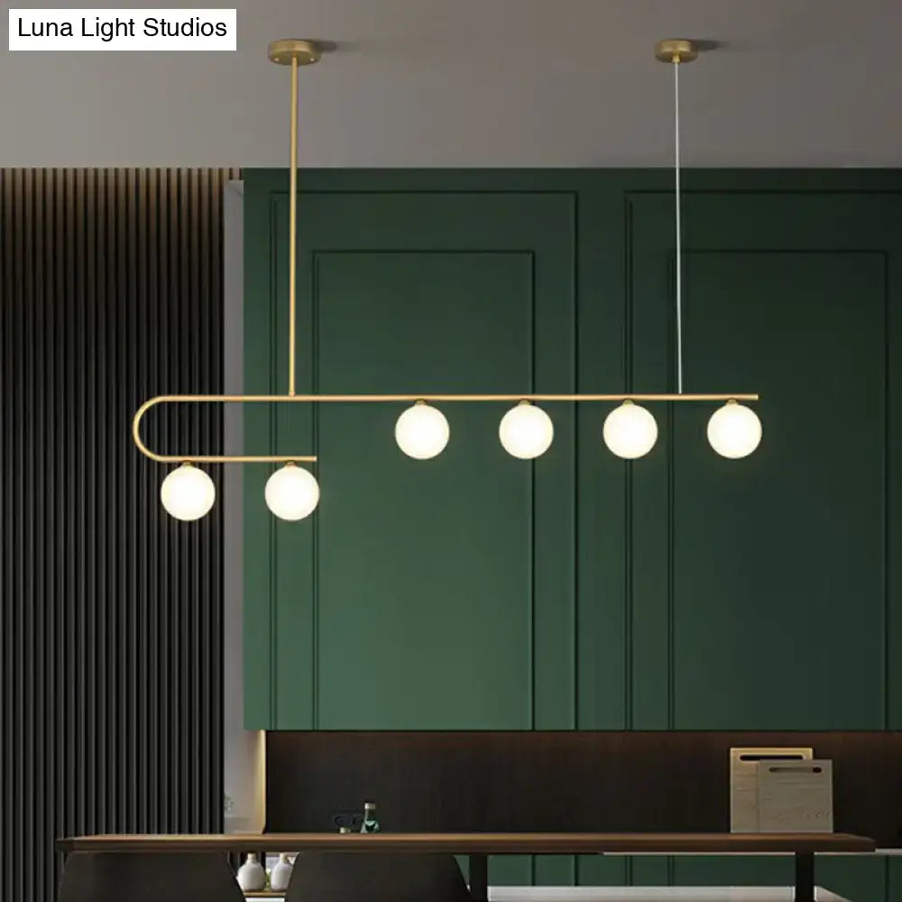 Modern brass DecorBites island pendant light with five frosted ivory glass globes in a sleek curved LED design