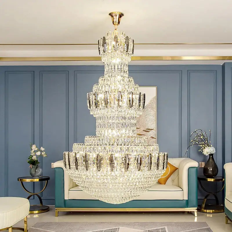 A multi-tiered postmodern gold and silver decorbites crystal chandelier hanging elegantly in a hotel lobby ceiling