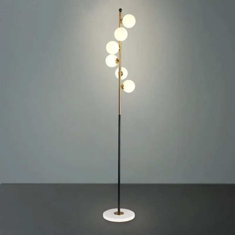 Postmodern gold and black glass floor lamp with five glowing white spherical bulbs and circular marble base for living room