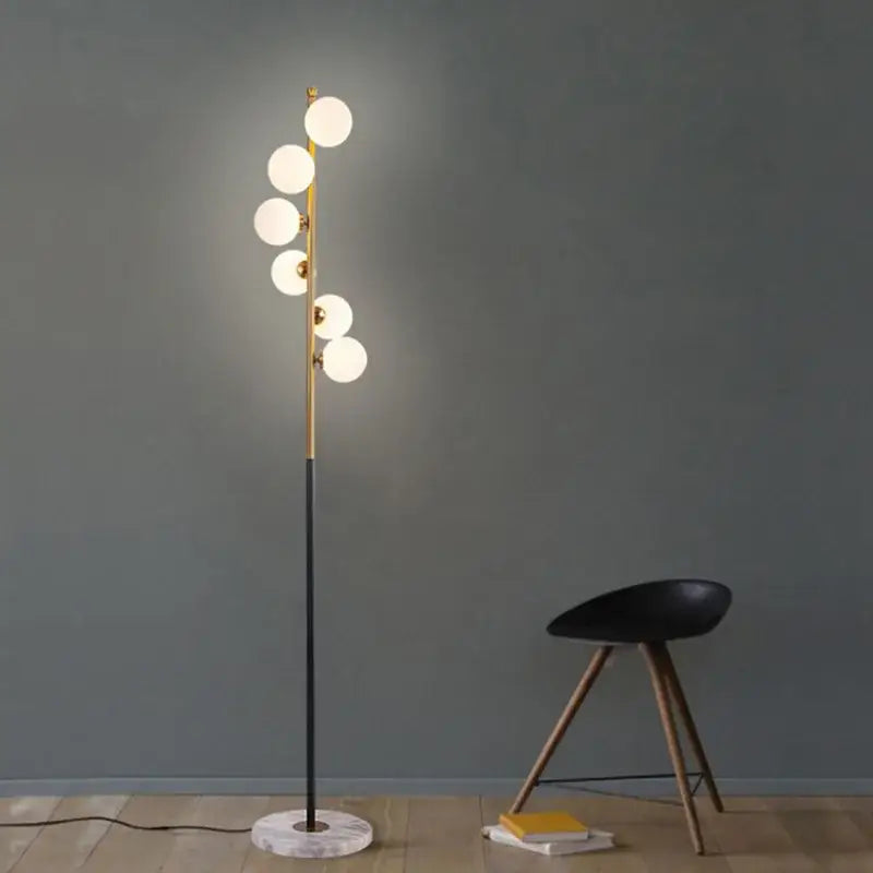 Postmodern gold and black glass floor lamp with slender pole, five white bulbs, and marble base for living room lighting