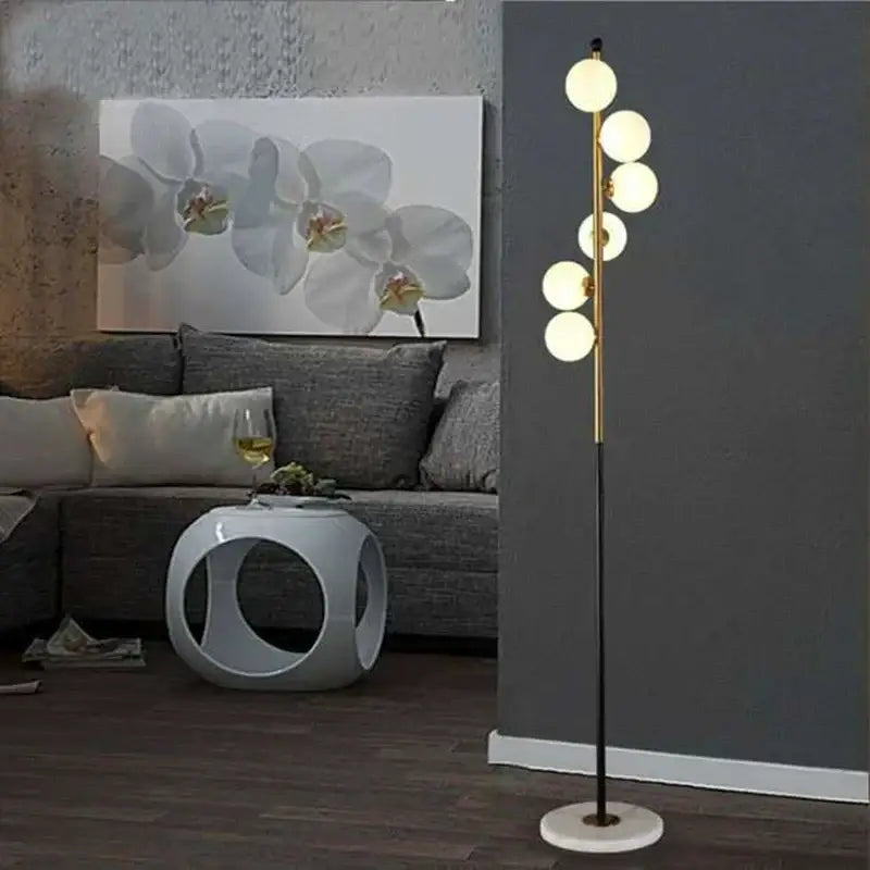 Postmodern gold and black glass floor lamp with five white bulbs on a slender pole and marble base for living room use