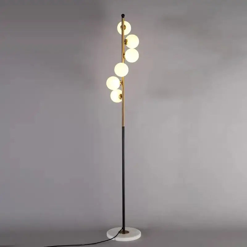 Postmodern gold and black glass floor lamp with slender brass pole, six white globes, and marble base for living room